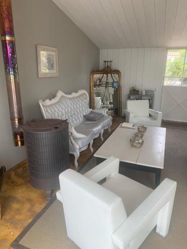 un salon avec des meubles blancs et une table dans l'établissement Beach Cottage, au Bois-Plage-en-Ré