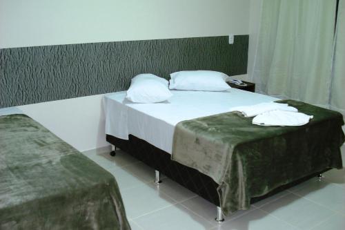 a bedroom with two beds with green sheets at Brisa Parque Hotel in Erechim