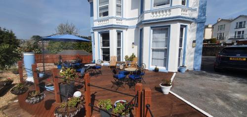 a house with a deck with tables and chairs at Tor Dean Guest House in Torquay