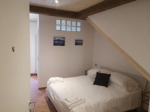 a bedroom with a white bed with a black pillow at Elicriso Apartment Affittacamere in Borzonasca