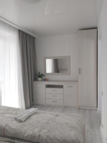 a white bedroom with a bed and a television at 2-х комнатная квартира in Taraz