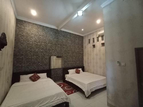 a bedroom with two beds in a room at Penginapan & Guest House Mbok Dhe Borobudur in Borobudur