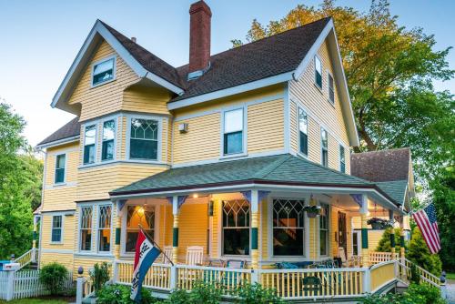 a yellow house with two american flags on the porch at Inn at the Oaks in Eastham