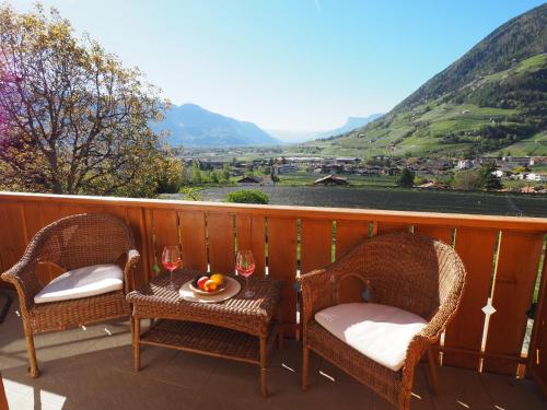 un balcón con 2 sillas y una mesa con copas de vino en Apartment zur schönen Aussicht, en Lagundo