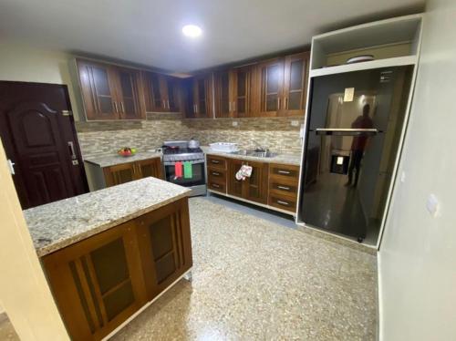 a kitchen with wooden cabinets and a black refrigerator at Casa Amueblada en el Centro de Navarrete in Villa Bisonó