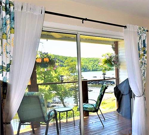 a living room with a sliding glass door with chairs at Peaceful 1st floor lakeside condo minutes from Osage Beach and Ozark State Park in Kaiser