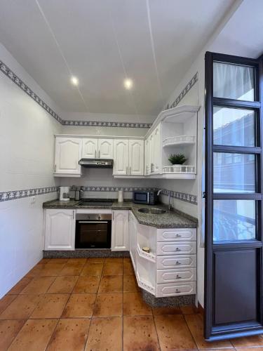 a kitchen with white cabinets and a wooden floor at Apartamento en el centro de Llanes in Llanes