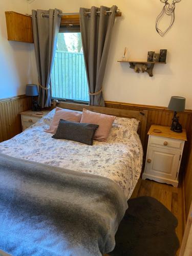 1 dormitorio con cama con almohadas y ventana en Cosy dog friendly lodge with an outdoor bath on the Isle of Wight en Whitwell