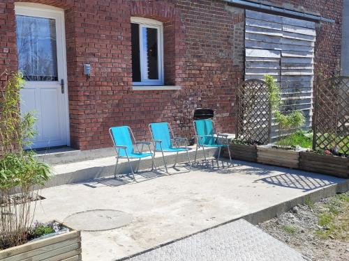three chairs and a grill in front of a brick building at la grange in Coigneux