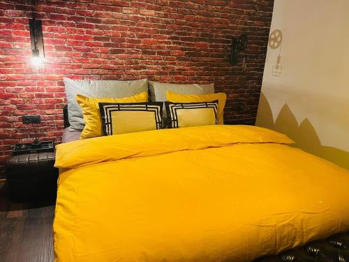 a yellow bed in a room with a brick wall at Villa 3 in Mediaş