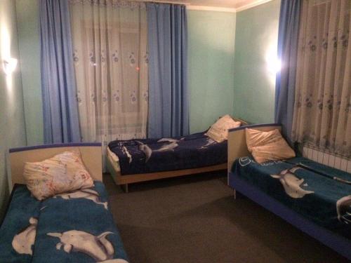 2 camas individuales en una habitación con cortinas y 2 camas individuales de vinilo en Hostel Ask, en Karakol