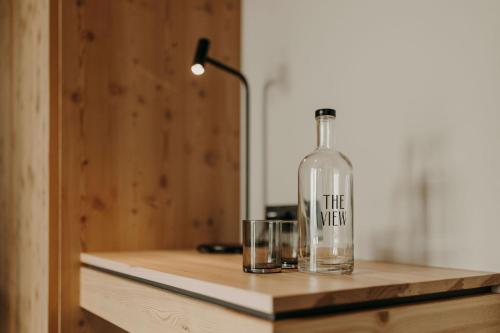 a bottle sitting on a wooden counter with a glass at Hotel VIEW - incl Joker Card in Summer in Saalbach Hinterglemm