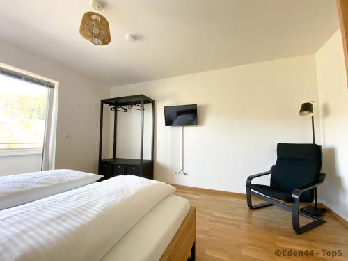 塔姆斯韋格的住宿－Eden 44 - Top 5，一间卧室配有一张床、一把椅子和电视