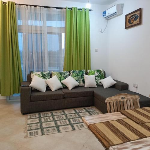 a living room with a couch and green curtains at HavenHouse Kijani - 1 Bedroom Beach Apartment with Swimming Pool in Malindi