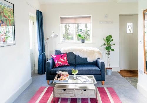a living room with a blue couch and a table at Chestnut Cottage at Gravel Farm in Stretham
