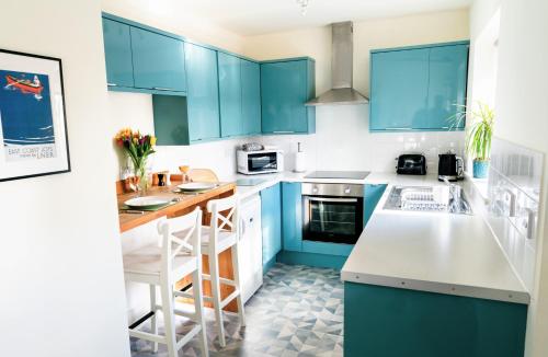 a blue and white kitchen with blue cabinets at Elm Cottage at Gravel Farm in Stretham