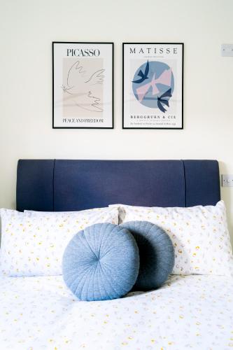 a bed with three pictures and a blue pillow on it at Elm Cottage at Gravel Farm in Stretham