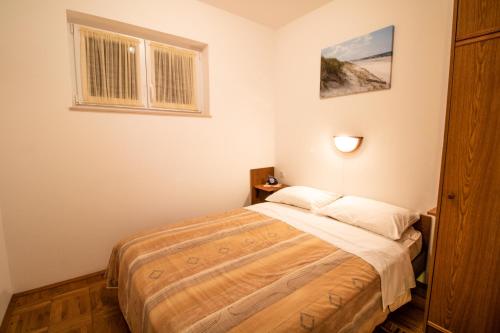 a bedroom with a bed and a window at Apartment Mario with Terrace and Sea View in Baška