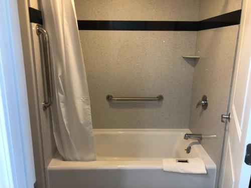 a bathroom with a bath tub with a shower curtain at Cali Inn in Carson