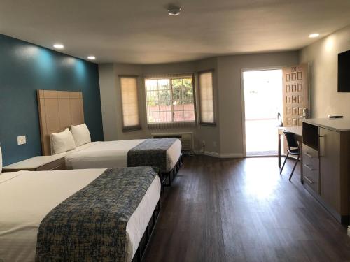 um quarto de hotel com duas camas e uma televisão em Cali Inn em Carson