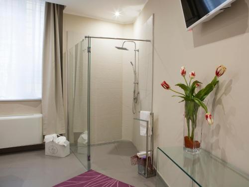 baño con cabina de ducha de cristal y jarrón de flores en B&B Lamezia Terme, en Lamezia Terme
