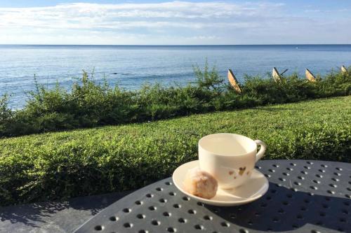 Una taza de café y un donut en una mesa cerca del océano. en Beach Villa Varna - cosiness 4 meters from the sea en Varna