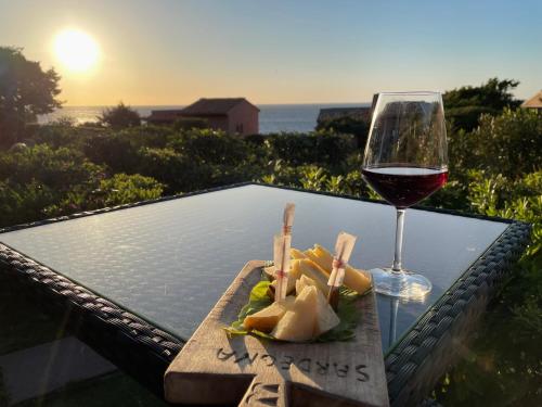 una mesa con una copa de vino y un plato de comida en Villetta La Risacca, en Costa Paradiso