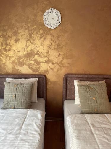 two beds in a room with a clock on the wall at Apartman studio Lusi 1 in Subotica