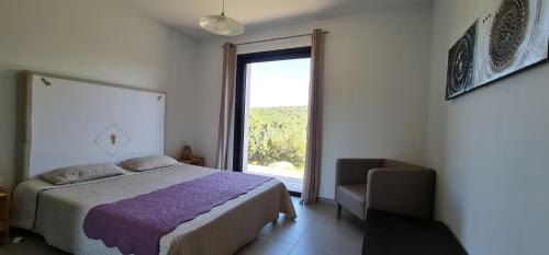 a bedroom with a bed and a window and a chair at Villa Giulia in Porto-Vecchio