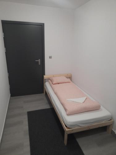 a bed in a room with a black door at Noclegi u Andrzeja in Gdańsk