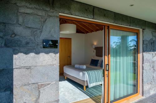 a bedroom with a bed and a stone wall at Quinta da Magnólia AR in Urzelina