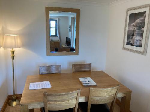 a dining room table with chairs and a mirror at Prince Croft Cottage in Porthtowan