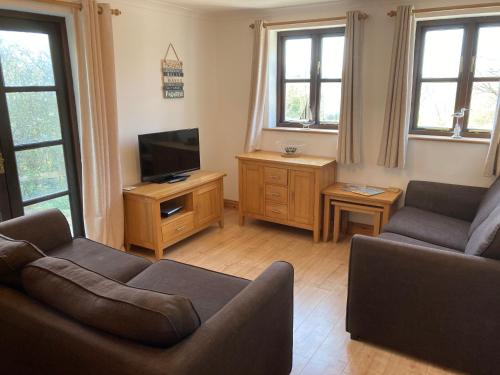 a living room with a couch and a tv at Prince Croft Cottage in Porthtowan