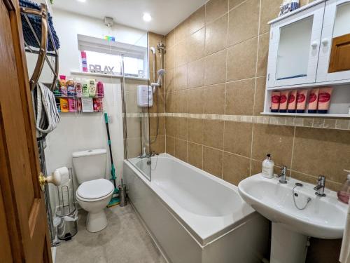 a bathroom with a tub and a toilet and a sink at 2 bedroom home in quiet location close to Chester in Hough Green