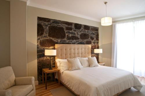 a bedroom with a large bed with a stone wall at The Docks in Paul do Mar