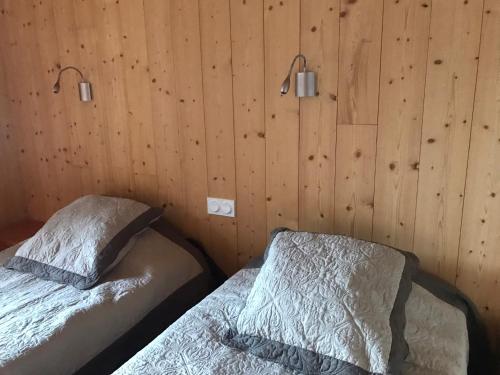 two beds in a room with wooden walls at Auberge du Glandon in Saint-Colomban-des-Villards