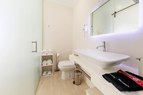 a white bathroom with a sink and a toilet at Quinta da Magnólia AR in Urzelina