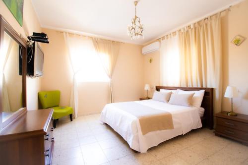 a bedroom with a white bed and a television at Sunlight Holiday Apartment in Arad