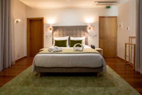 a bedroom with a large bed with a green rug at Quinta da Magnólia AR in Urzelina