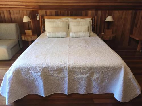 a large white bed with two pillows and a couch at Chalé Romântico - Gramado in Gramado