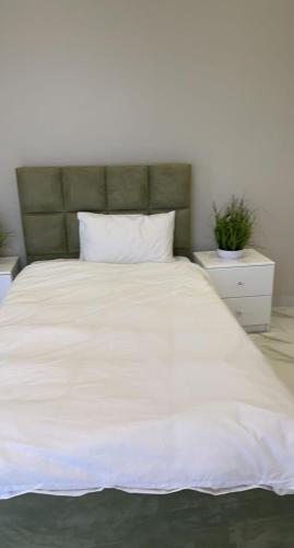 a large white bed with a green headboard at Al Ghadeer Maison Masfout in Sharīyah