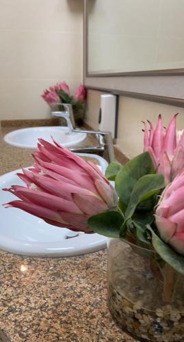 a bunch of pink flowers in a vase on a counter at Al Ghadeer Maison Masfout in Sharīyah