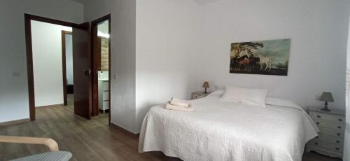 コニル・デ・ラ・フロンテーラにあるChalet en Rocheの白いベッドと壁に絵画が飾られたベッドルーム1室