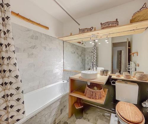 a bathroom with a sink and a tub and a toilet at Le soupir des palmiers. Idéal couple, piscine, mer in La Grande-Motte