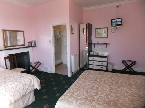 a bedroom with pink walls and a bed and a fireplace at Elgin Villa in Bath