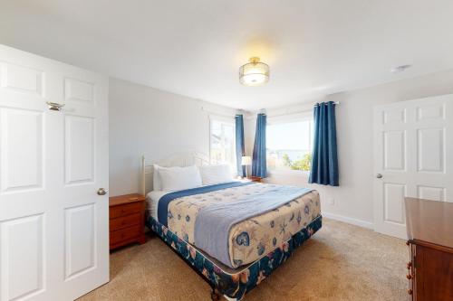 a bedroom with a bed with blue curtains and a window at Alsea Sands in Waldport