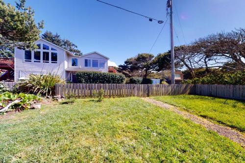 a white house with a fence in a yard at Alsea Sands in Waldport