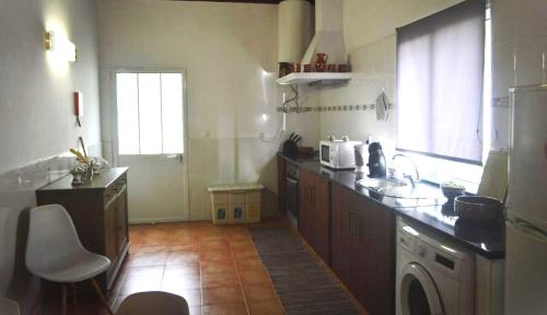 a kitchen with a sink and a washing machine at Cantinho do Sol in Mosteiros