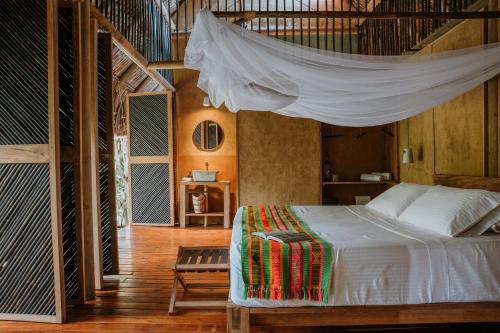 a bedroom with a bed with a mosquito net at Dos Aguas Lodge in Rincón