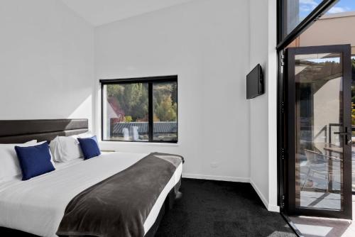 - une chambre avec un lit et une grande fenêtre dans l'établissement Penthouse Apt 24 at the base of Coronet Peak, à Queenstown
